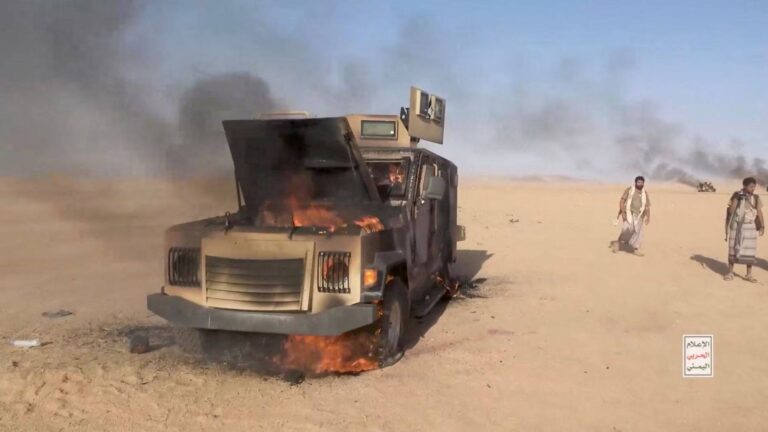 Houthi fighters beside a destroyed vehicle in Yemen (file photo via Reuters/Firstpost)